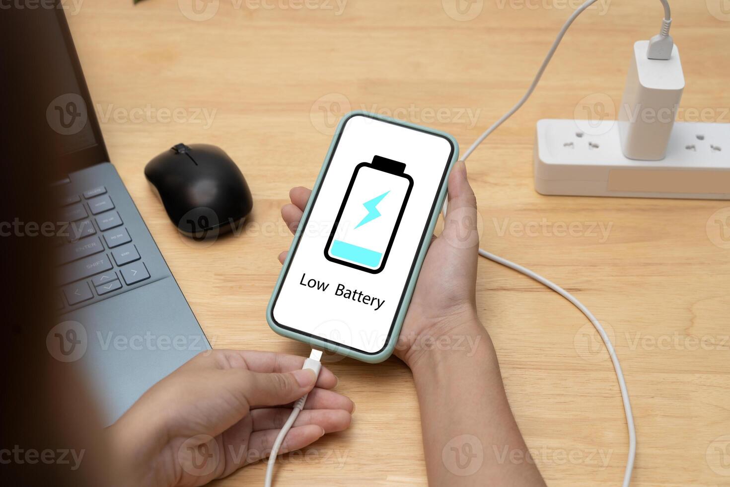 Hand charging smartphone with low battery icon on screen, technology, power supply and energy concept photo