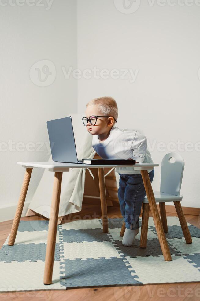 A Focused Child Happily Engaged in Learning at a Small Desk While Using a Laptop This Represents an Inspirational and Playful Approach to Education Nurturing Creativity and Curiosity photo