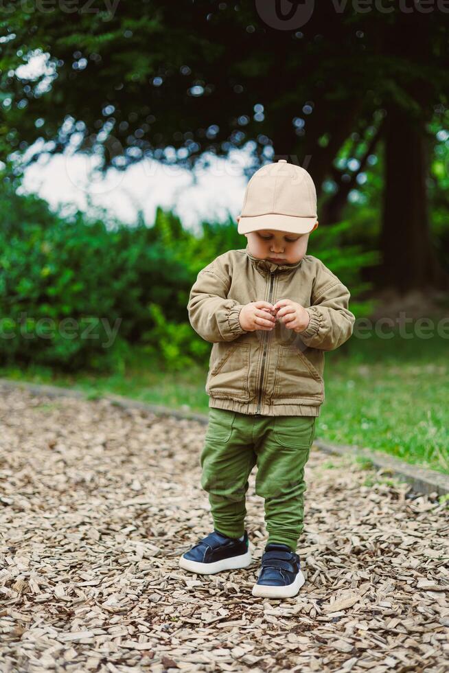 A cheerful toddler in a stylish outfit and cap delights in exploring the vibrant playground, embodying carefree childhood joy, laughter, and playful charm that fills the air with warmth photo