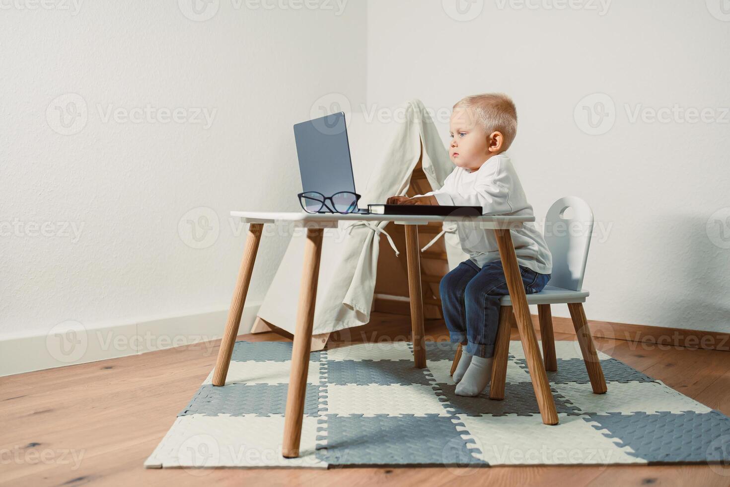 A young child is engaged with a laptop at home, surrounded by a creatively designed environment that promotes learning and exploration, encouraging creativity and joy in their childhood development photo