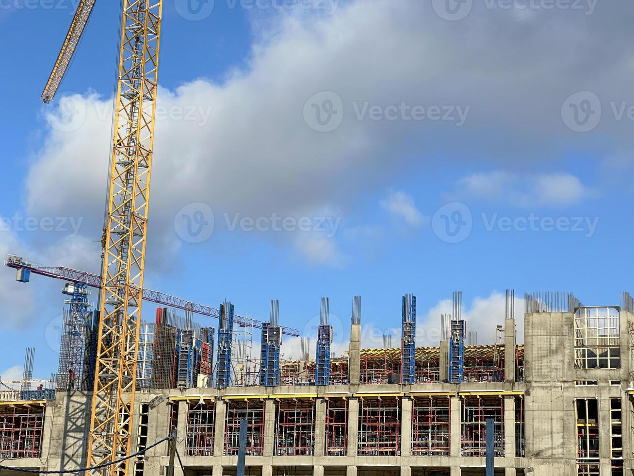 Construction site with cranes and scaffolding under a blue sky. Building structure in progress with visible construction materials and equipment. photo