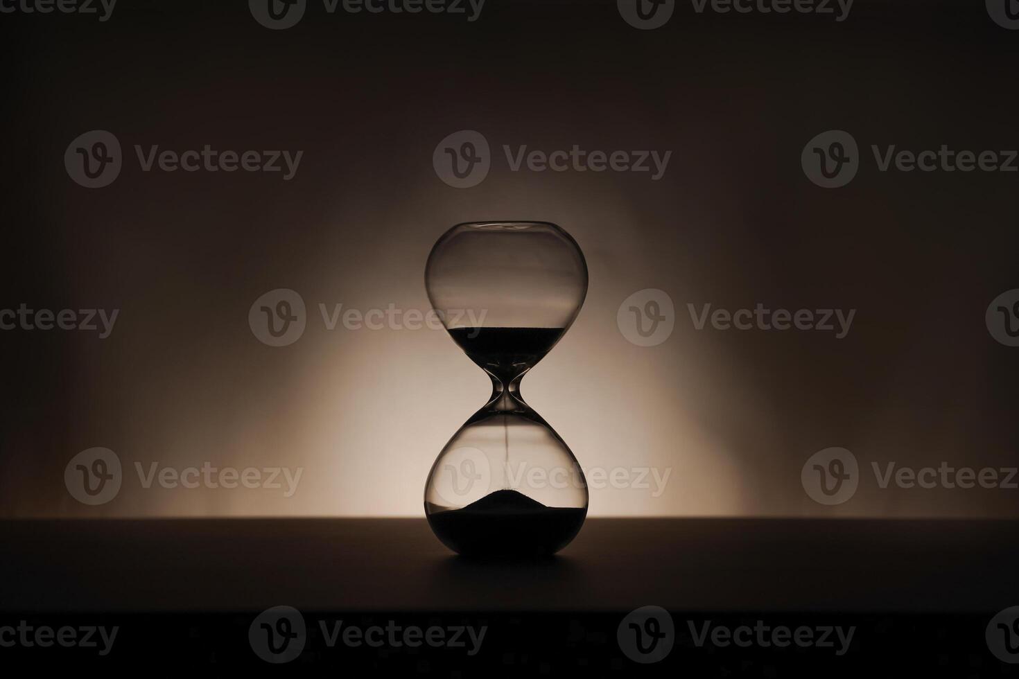 A simple hourglass on a wooden table with a beige backdrop, symbolizing time flow and minimalistic living. Running out of time, uncluttered presentation for stylish concepts photo