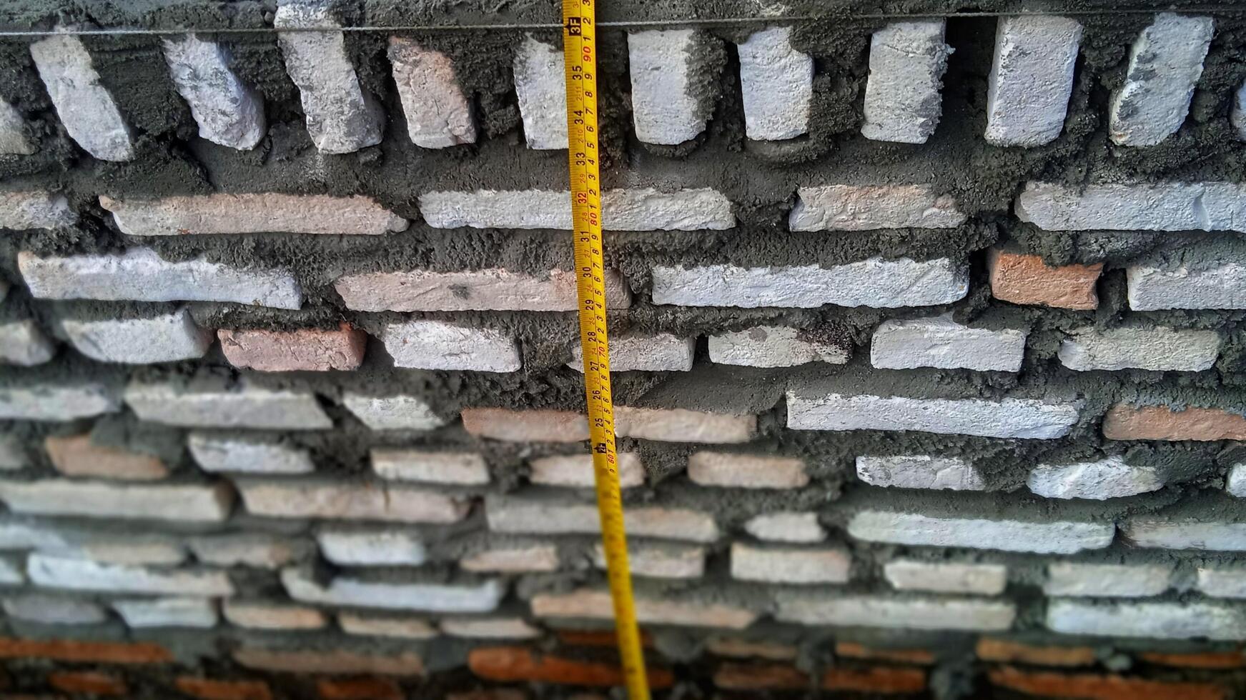 Measuring the height of the red brick masonry on the building foundation photo