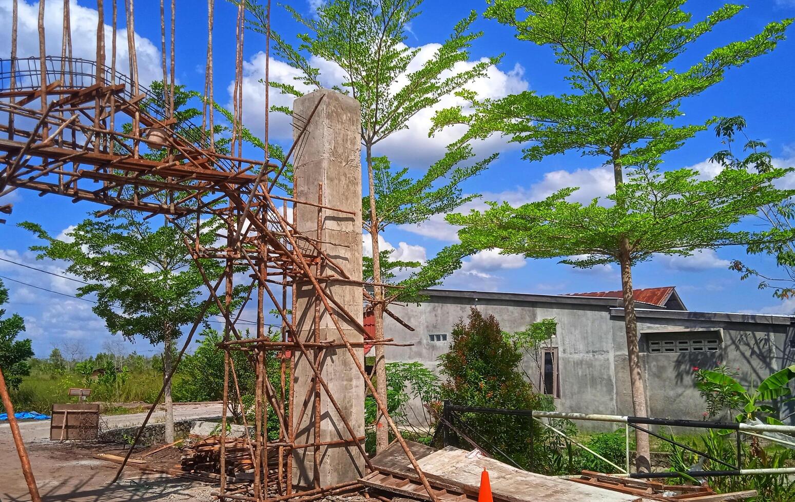 Wooden frame structure at a construction site with a wide cloudy sky and bright sun behind it. photo