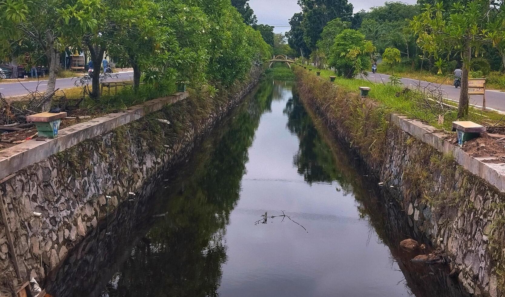 A canal that is lined with trees and grass photo