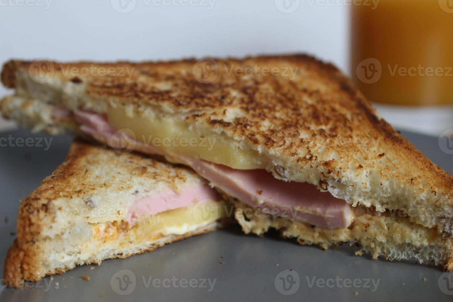 breakfast Sandwiches ham cheese and vegetable elenium lie on a gray plate next to the juice of orange apricot on the table. Cooking breakfast photo