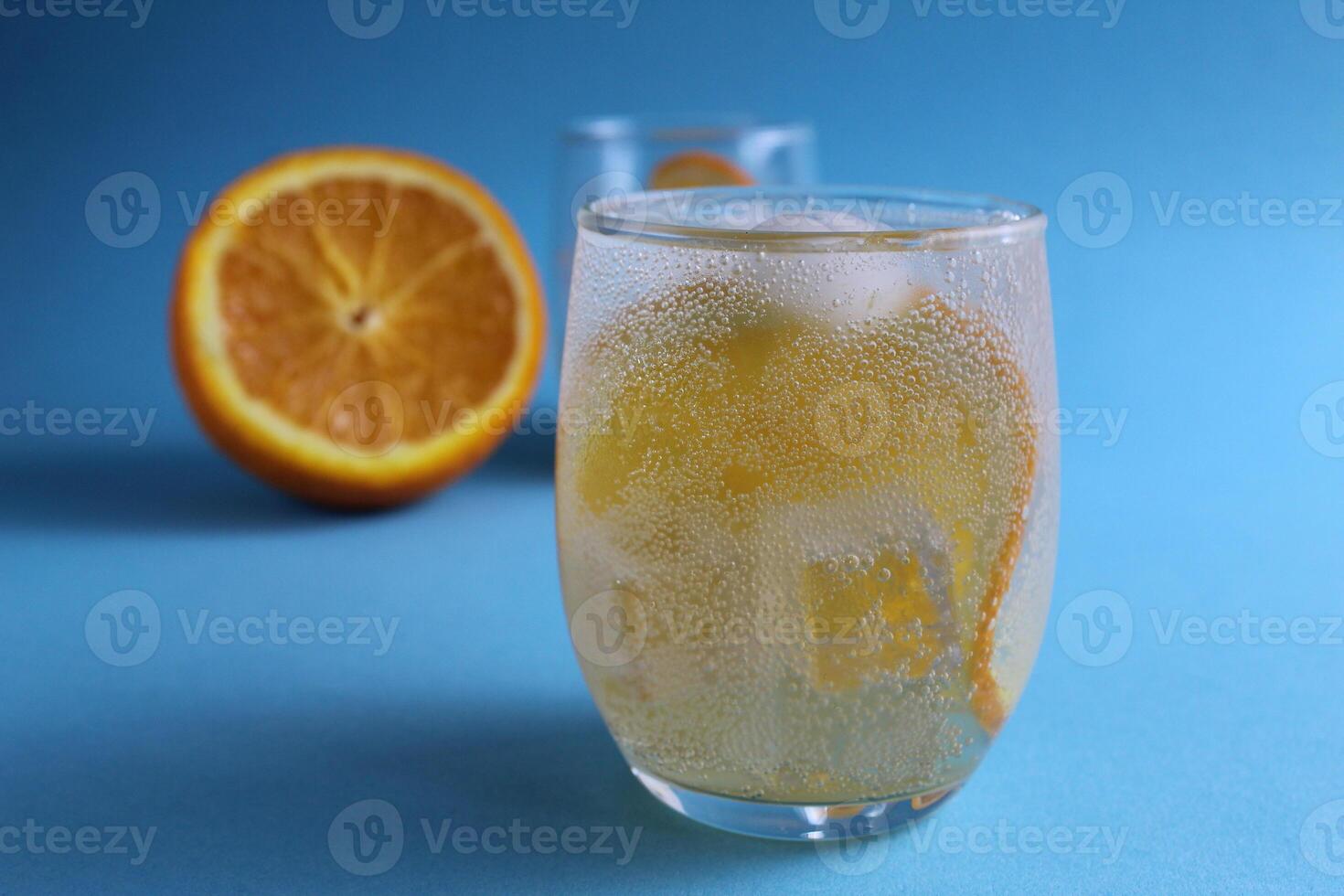 Step-by-step making of lemonade. Step 2. Pour the fruit orange with soda water. A glass lemonade orange on a blue background with a place for text . close-up photo