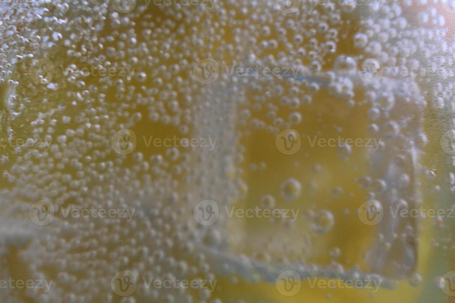 Lemonade water divorcing in a glass of ice and orange is close-up. Macrophoto photo