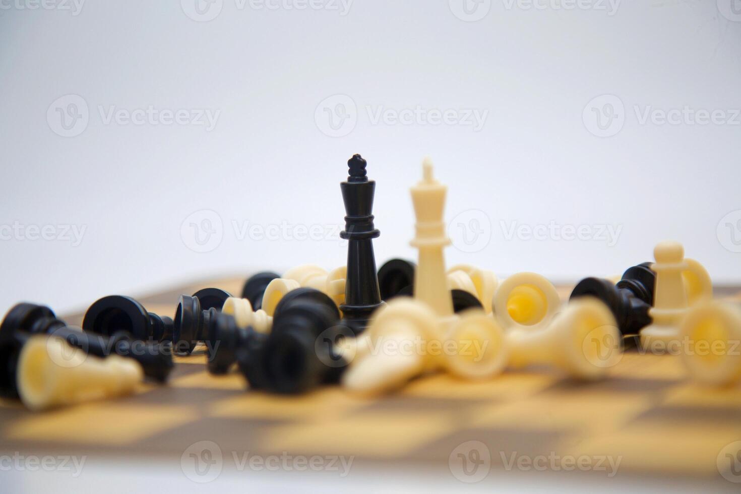 A chessboard, displaying a cluster of black and white chess pieces in a dynamic arrangement. The pieces are positioned in a somewhat chaotic manner, suggesting a game in progress.. photo