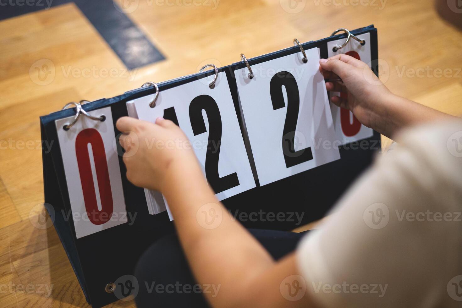 Close up of a manual flip scoreboard on a gym floor, its cards showing 0 19 4 0 as a game unfolds, capturing the tactile intensity of live sports and every crucial point swing. photo