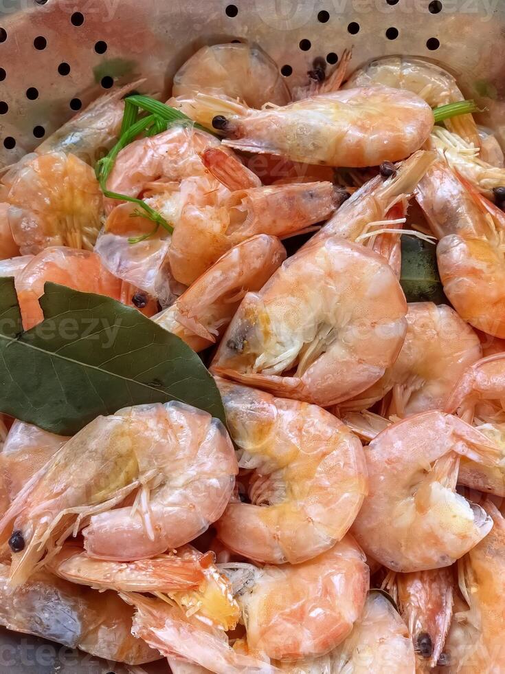 Fresh shrimp boiled with spices rest in a colander photo