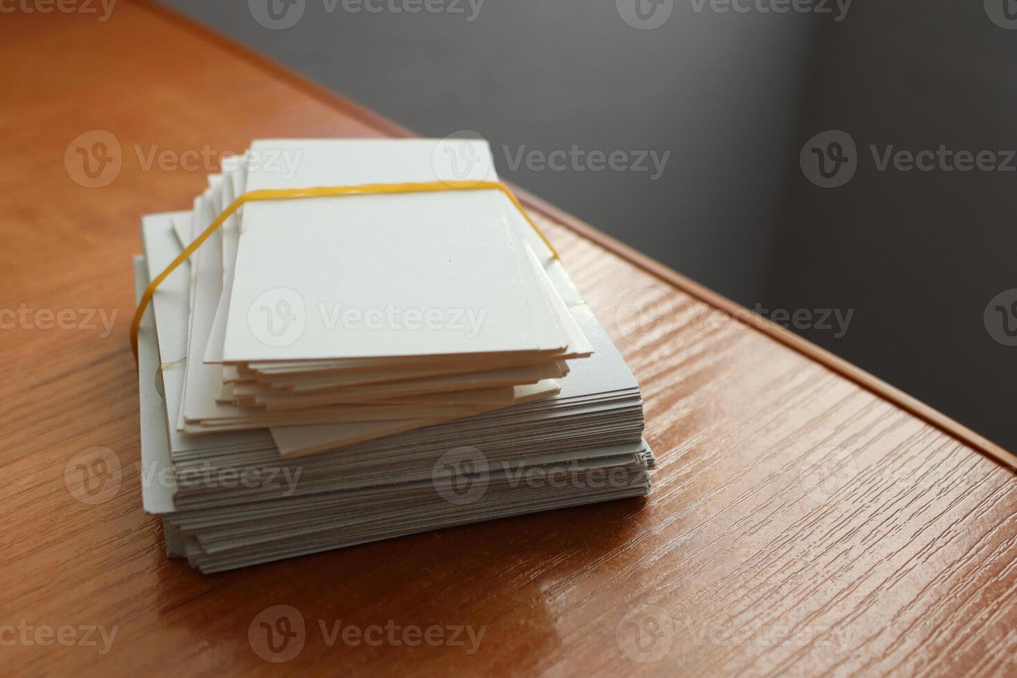 A stack of blank business cards is bound with a rubber band on a polished wooden surface photo