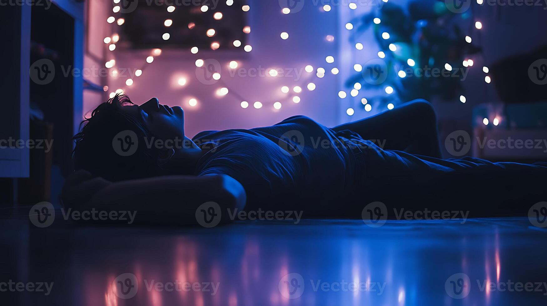 A person lying on the floor under string lights, staring at the ceiling at midnight, room dimly lit in blue and violet tones, cinematic realism, emotional solitude, film grain effect photo