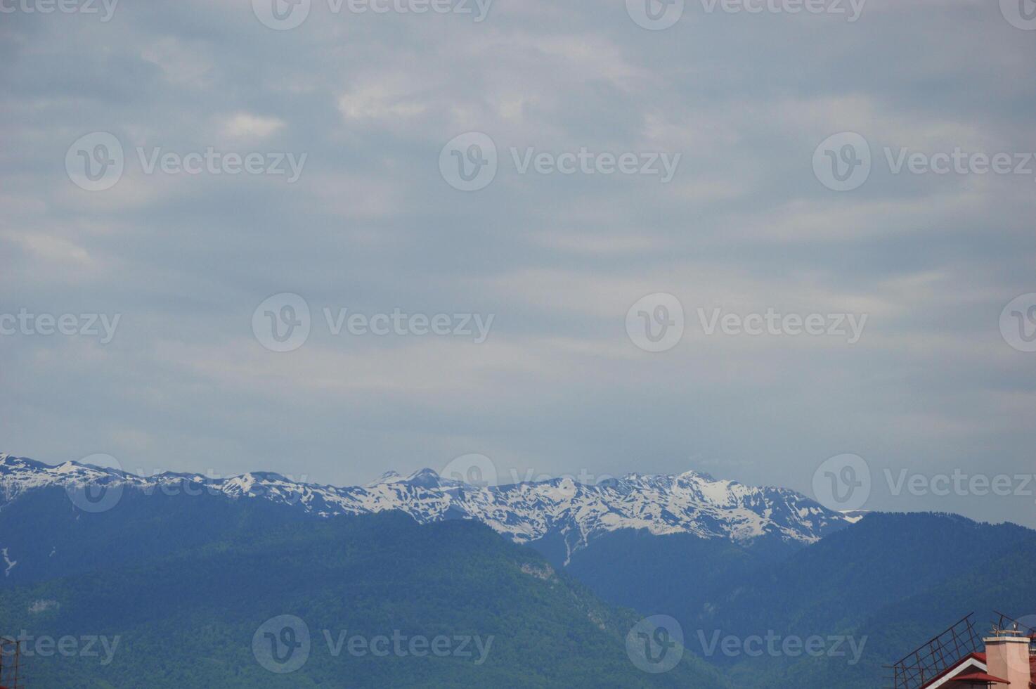 Snowy mountain peaks against the blue sky with white clouds. Sochi, Russia. photo