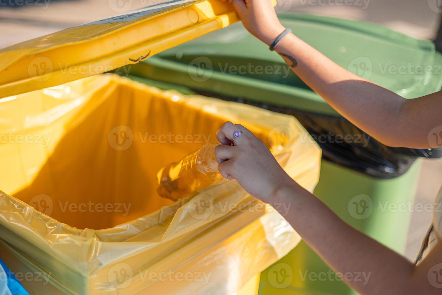 Woman throwing plastic bottle in yellow recycling bin promoting environmental awareness photo