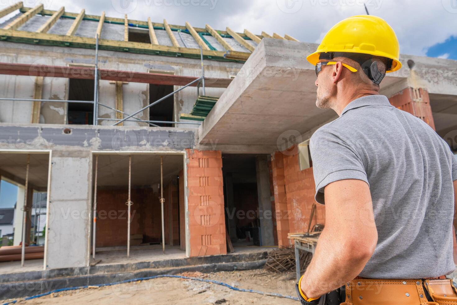 Construction Worker Observes Progress of New Building in Urban Area With Scaffolding photo
