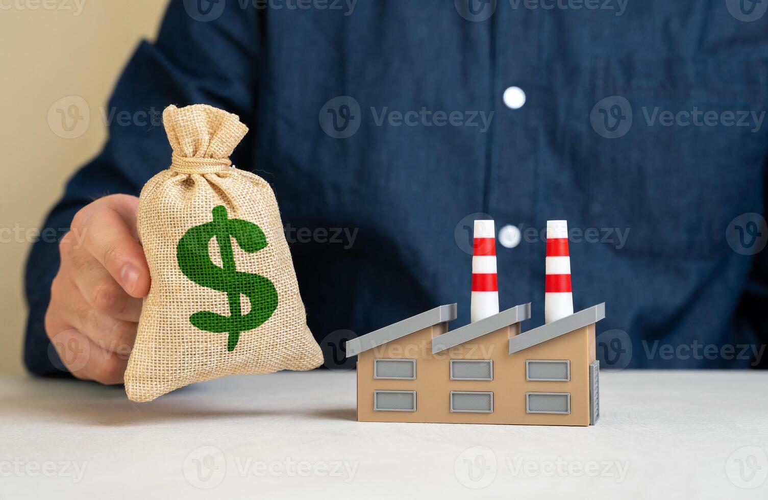 Man holding dollar moneybag near factory. Purchase of industrial assets and production. Investments and development of industry. Capital infusion into manufacturing, infrastructure upgrades photo