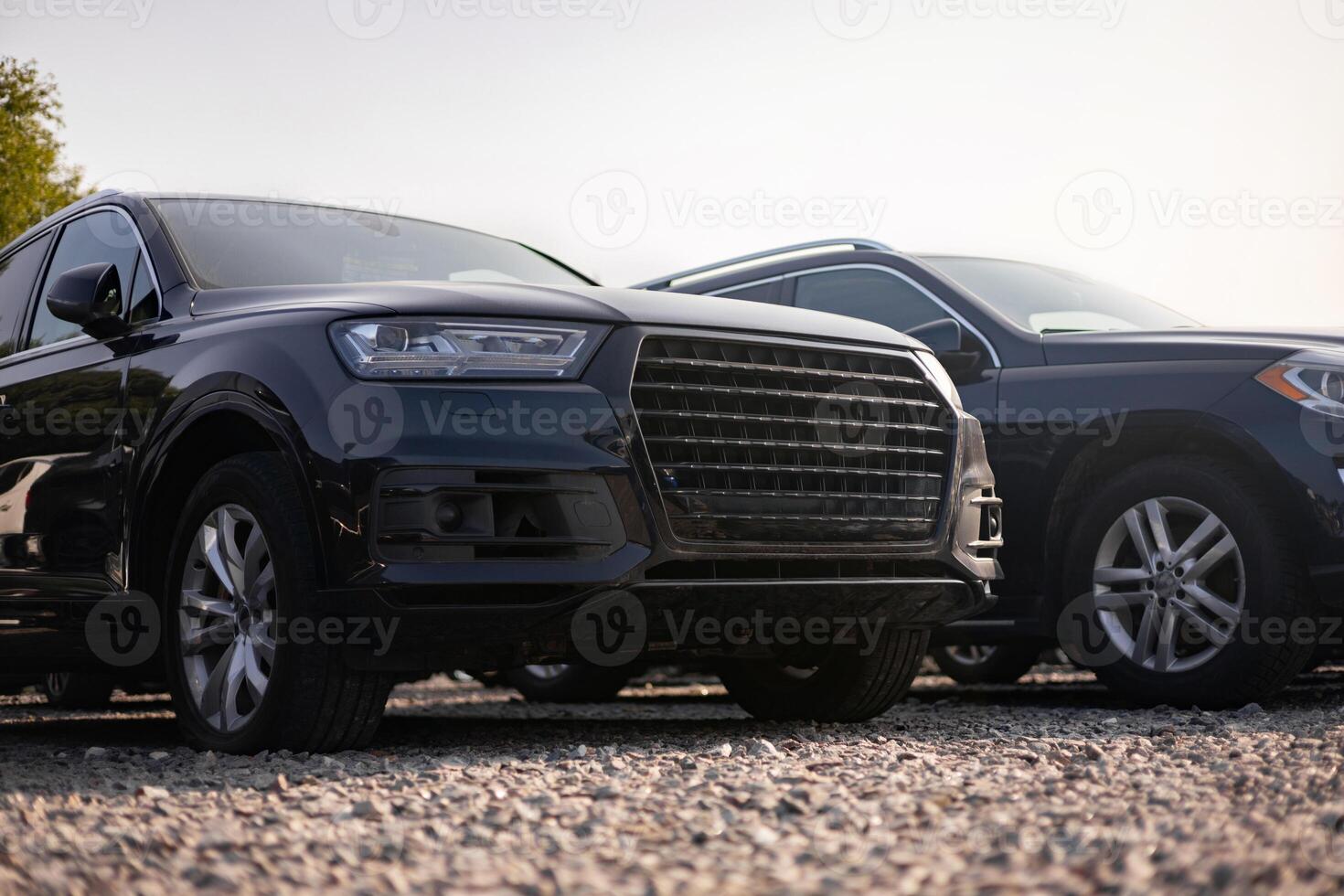 Two black SUVs parked outdoors on a gravel surface, showcasing modern car design. photo