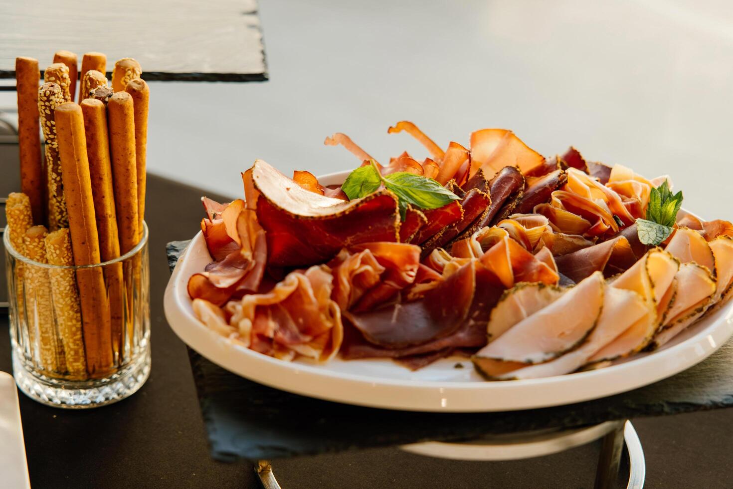 An Exquisite Display of Charcuterie Featuring Delicately Cured Meats, Artfully Arranged on a Platter Accompanied by Crunchy Breadsticks for a Gourmet Experience photo
