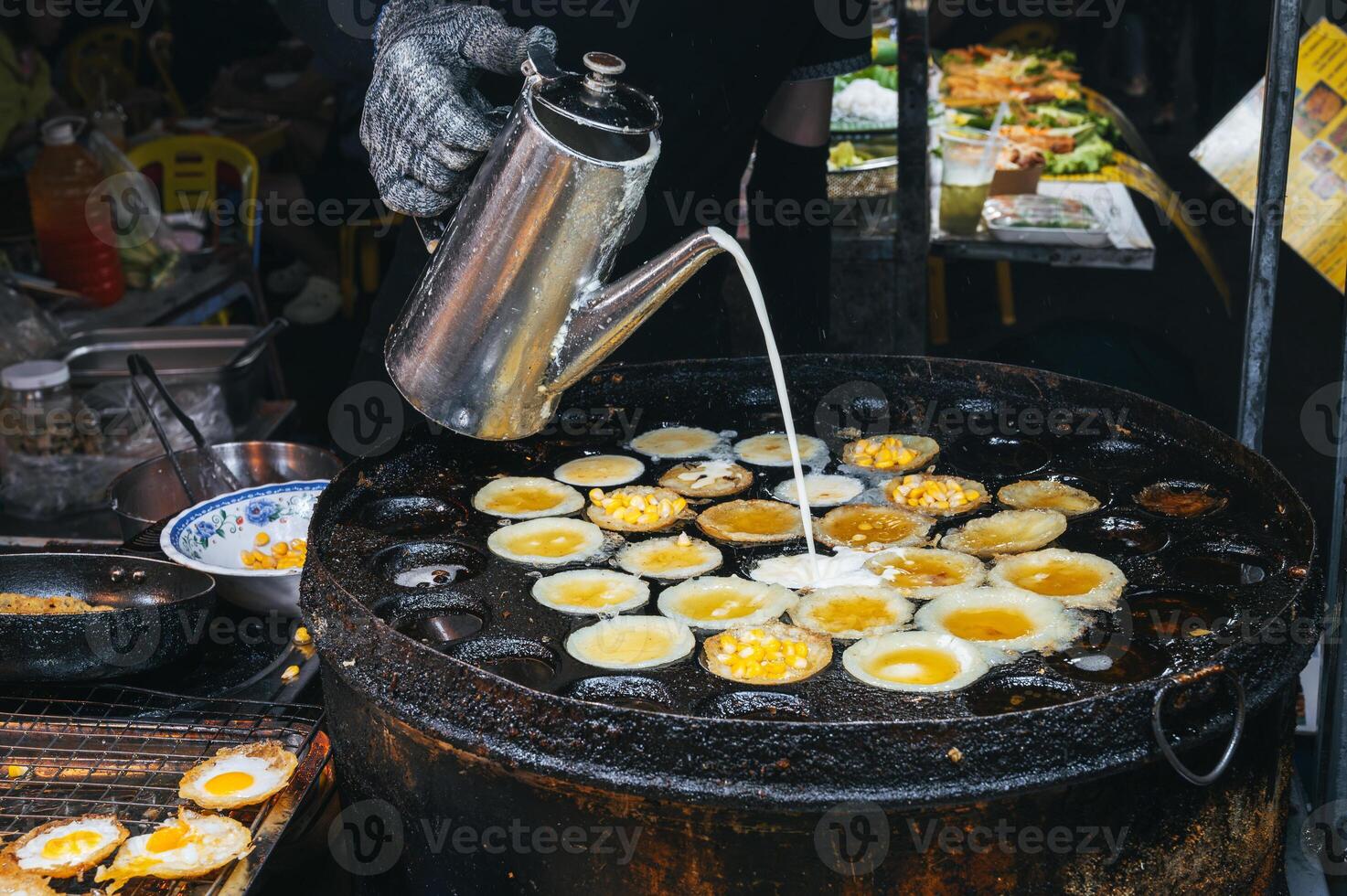 cooking a traditional Vietnamese dish Banh Khot with corn at an Asian night market on street in Vietnam in Asia photo
