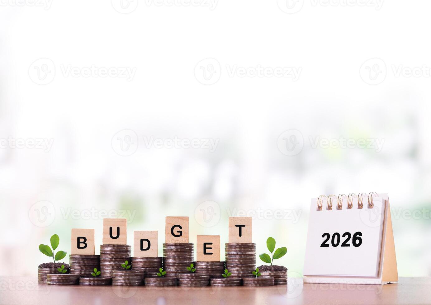 2026 desk calendar, Wooden blocks with the word BUDGET and plants growing up on stack of coins. The concept about budget planning and allocation in year 2026 photo
