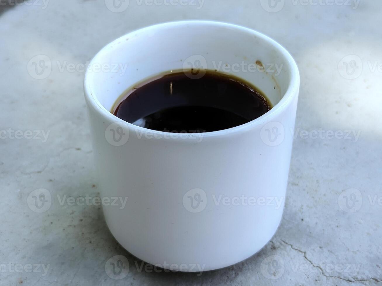 a cup of coffee sitting on a concrete surface photo
