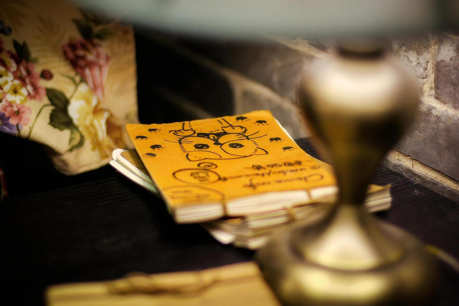 Still Life of a Sketchbook on a Dark Wooden Table with Gold Lamp and Floral Cloth photo