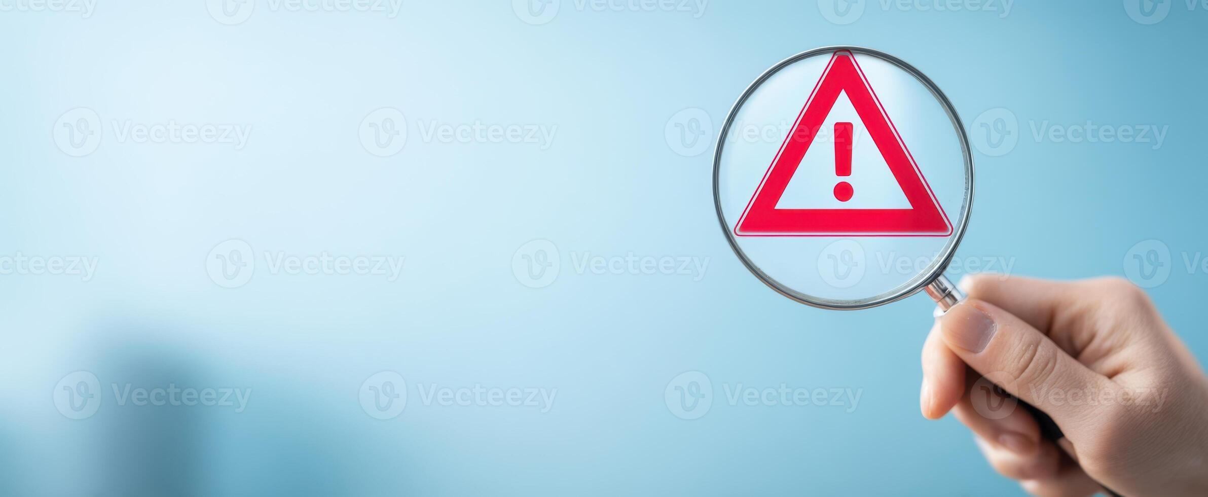 The warning sign highlighted through a magnifying glass held in hand. photo