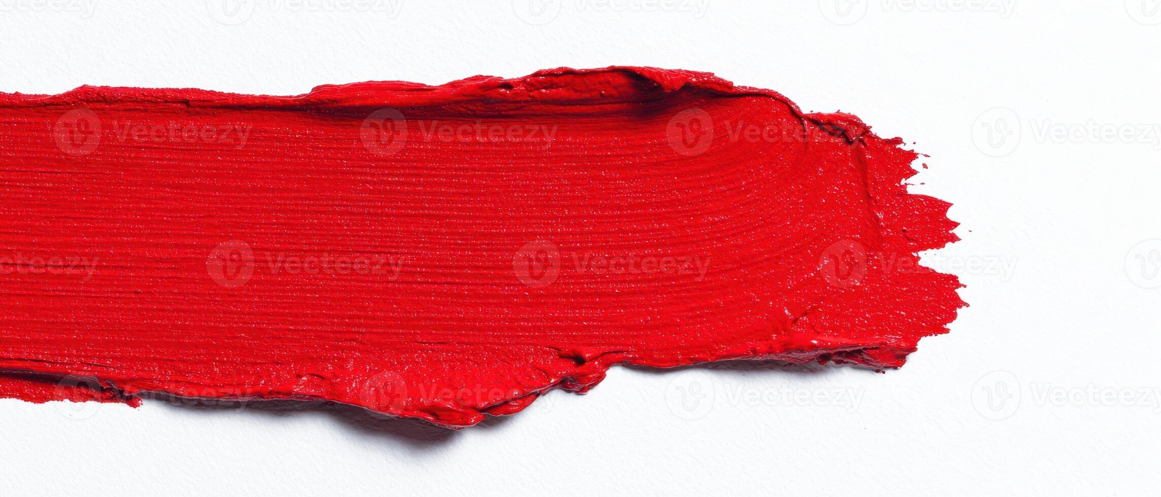 The vibrant red paint stroke across a clean canvas background. photo