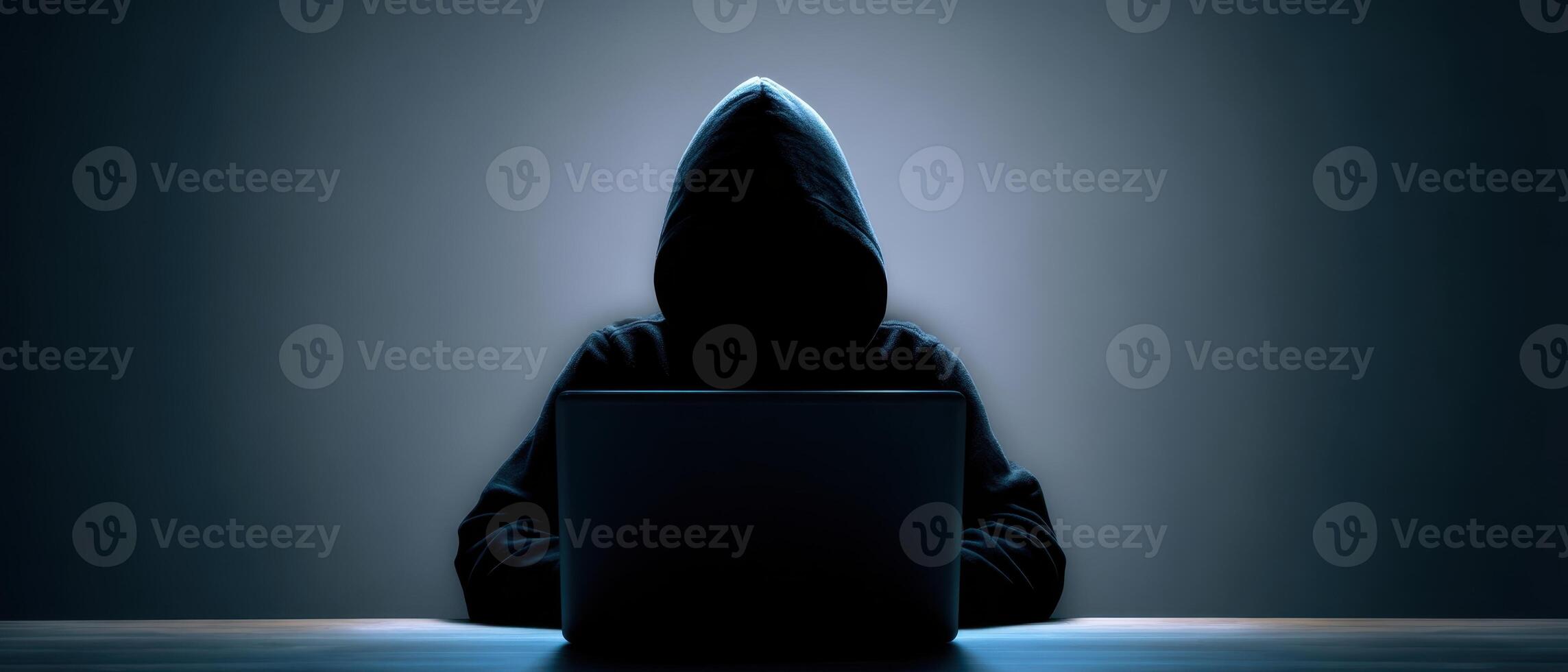 The mysterious hacker intently working on a laptop in a dark setting. photo