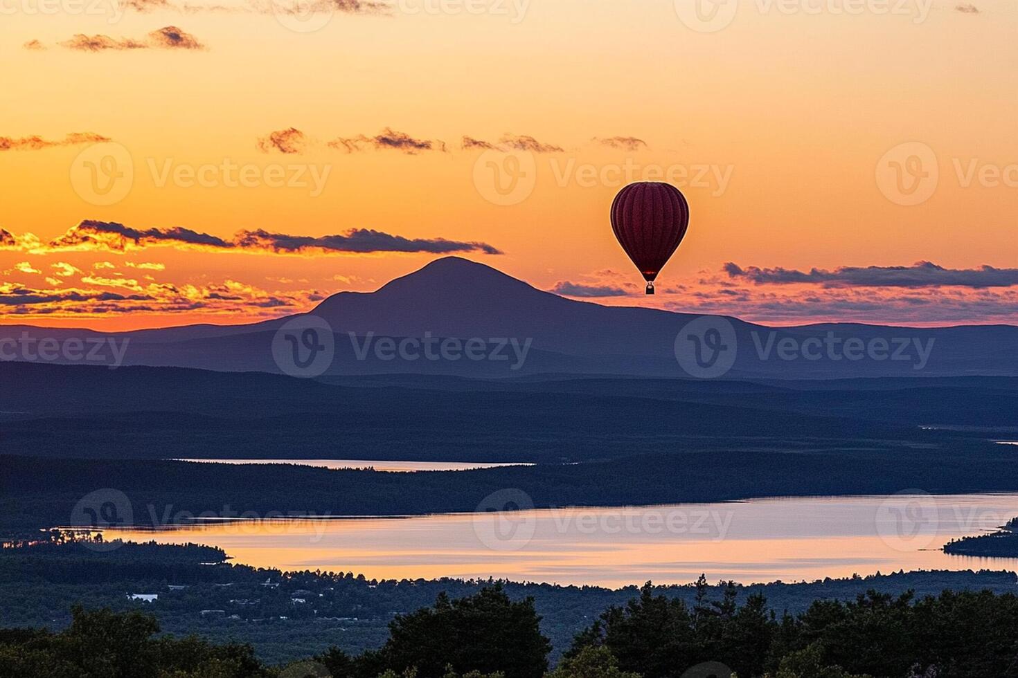 A hot air balloon flies over a lake and mountains at sunset photo