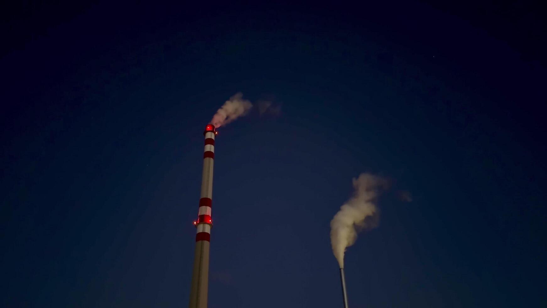 Industrial Emissions Stacks are silhouetted against a Dark Sky at night, highlighting concerns photo