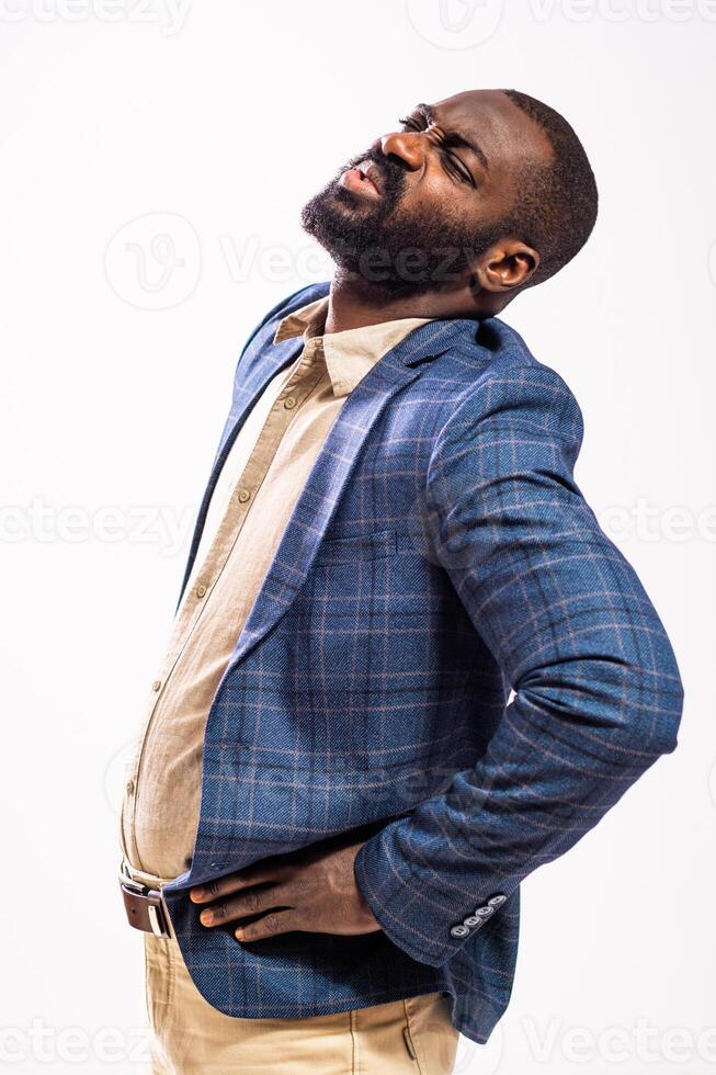 Distraught black male manager experiencing back sprain and fatigue, expressing frustration and emotional stress in a studio portrait. photo
