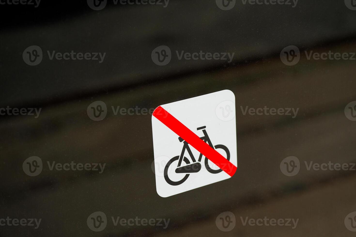 At a window is a sign indicating that bicycles are prohibited, the sidewalk is reflected photo