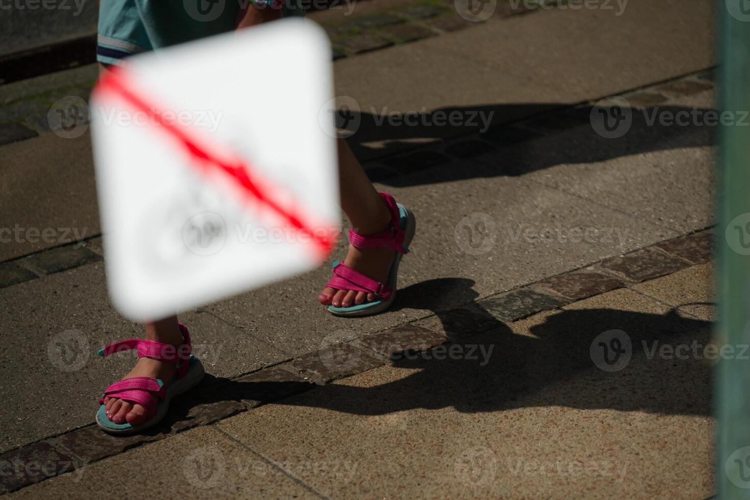 In a window is a sign bicycles are prohibited, reflecting a sidewalk with a child walking by photo