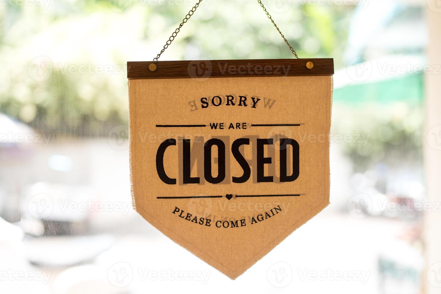 Closed sign in which is hanging at the glass front door of coffee shop. Sign and symbol for business. photo