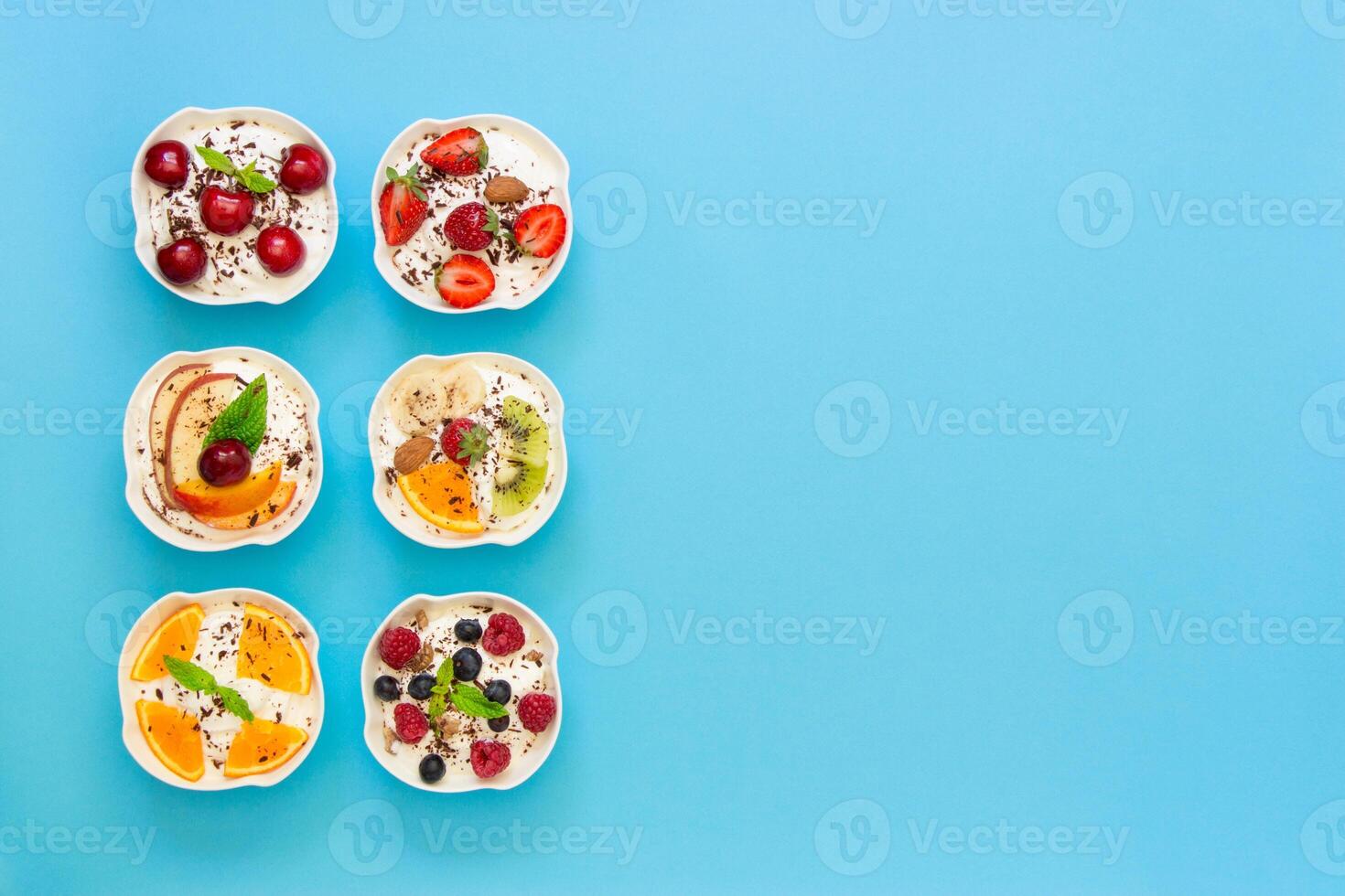 Left 6 different yogurts displayed vertically in 2 rows of 3 pieces, right empty space on light blue background. Six yogurts and empty space. Horizontal. Top view. photo