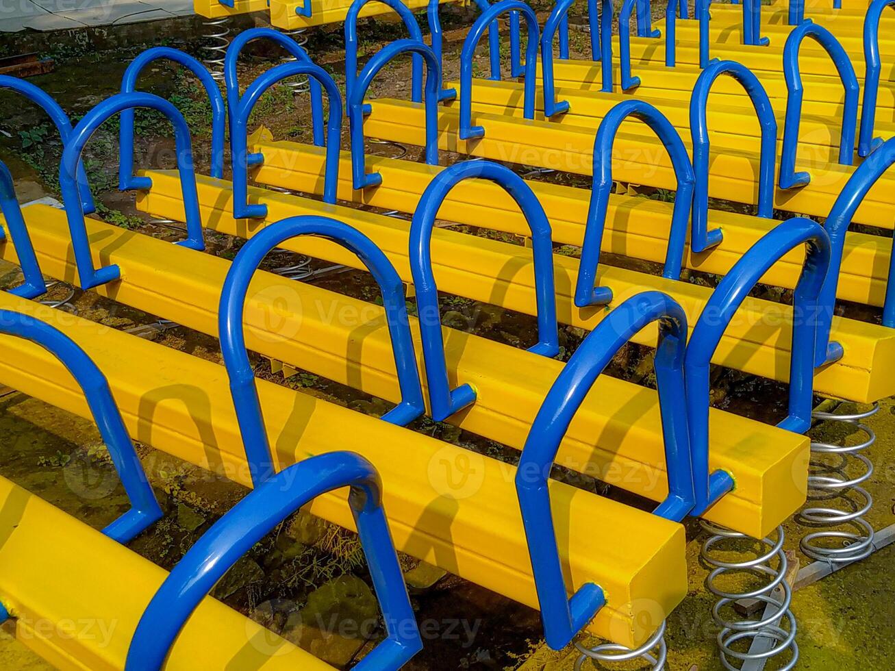 Repeating Rows of Yellow and Blue Playground Seesaws photo