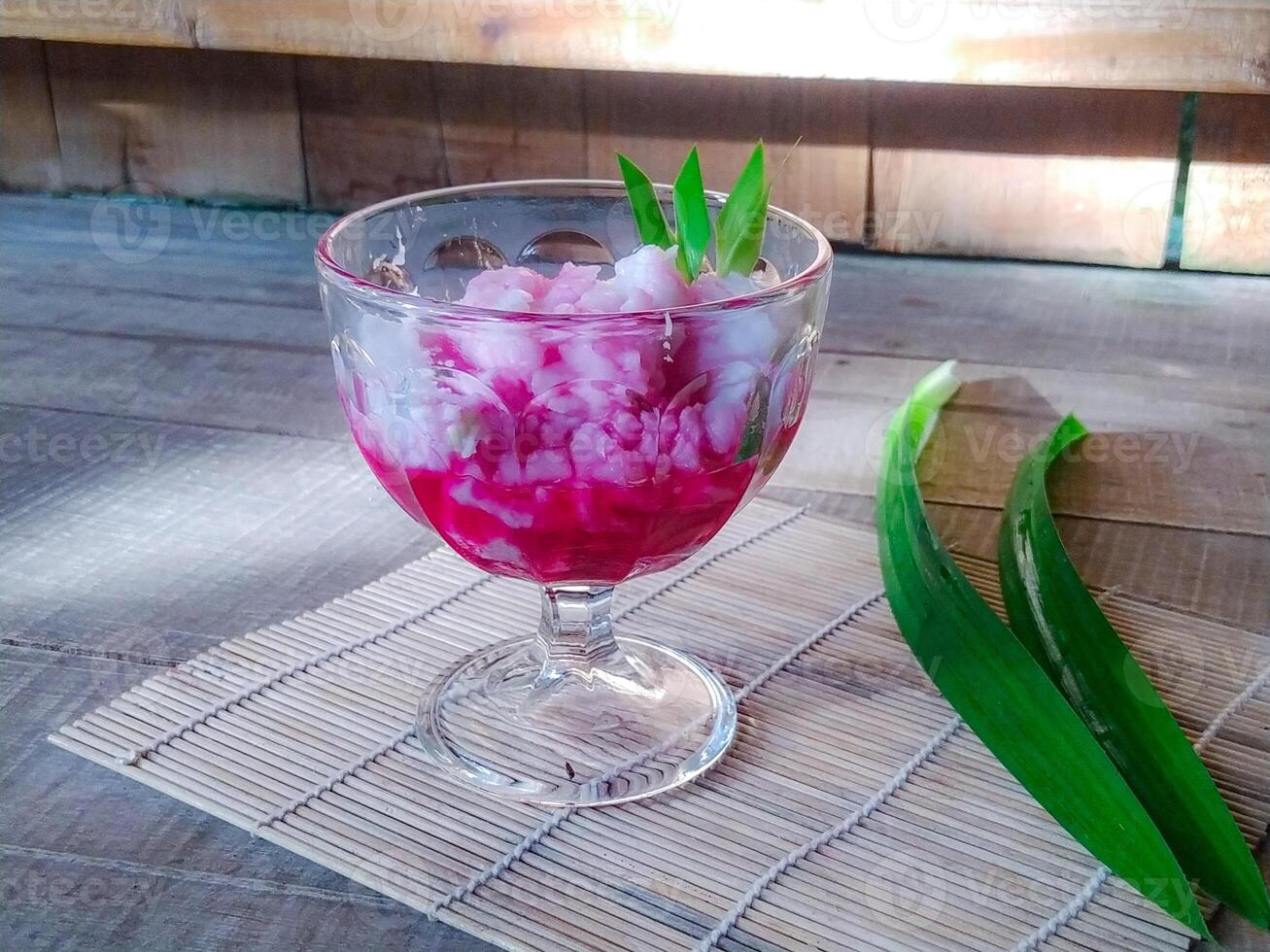 A glass of pink liquid with a green leaf photo