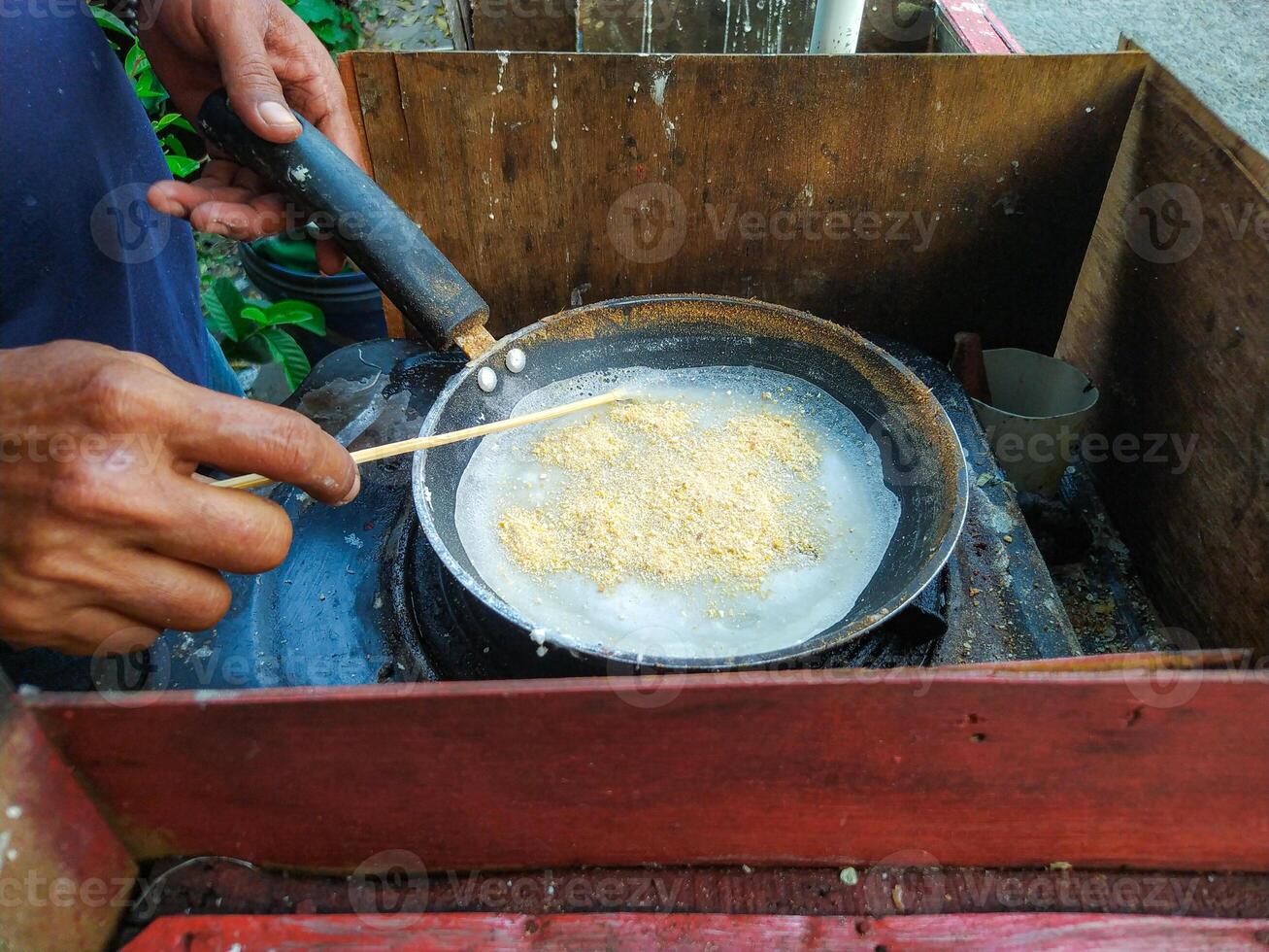 A person stirring a pot of food with a stick photo