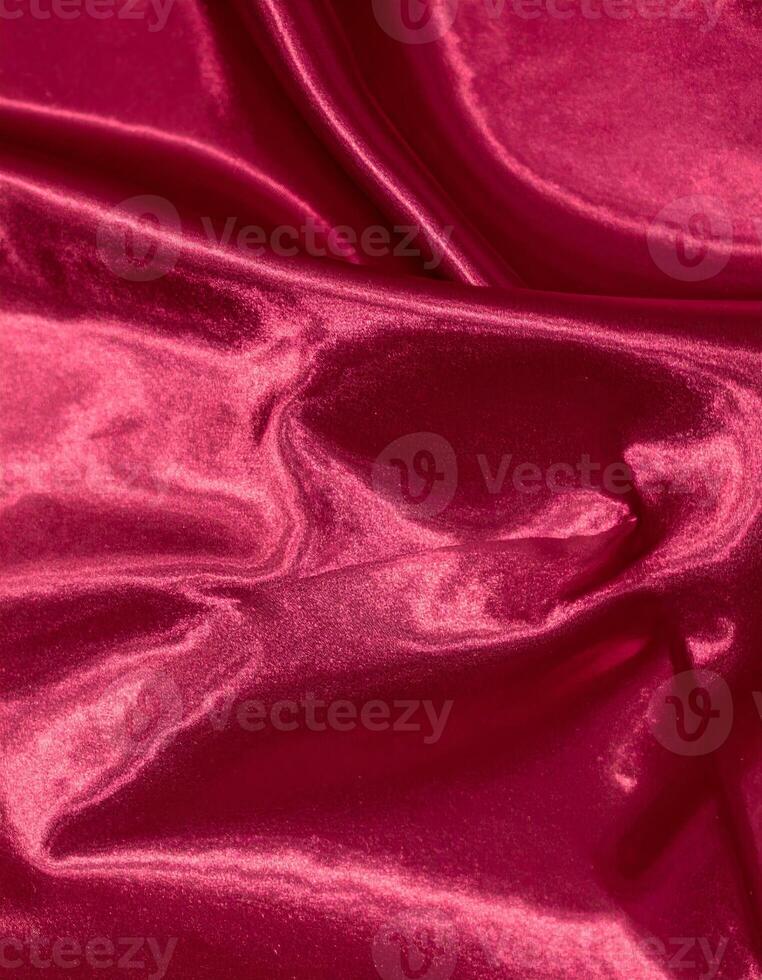 Close-up of a shiny, deep red silk fabric surface with a smooth texture photo