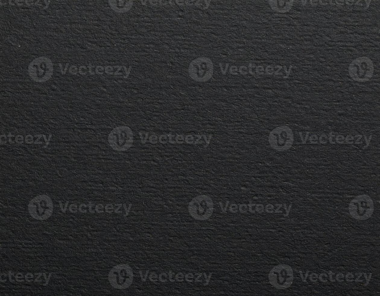 Close-up of a dark, coarse paper surface with a textured pattern background. photo
