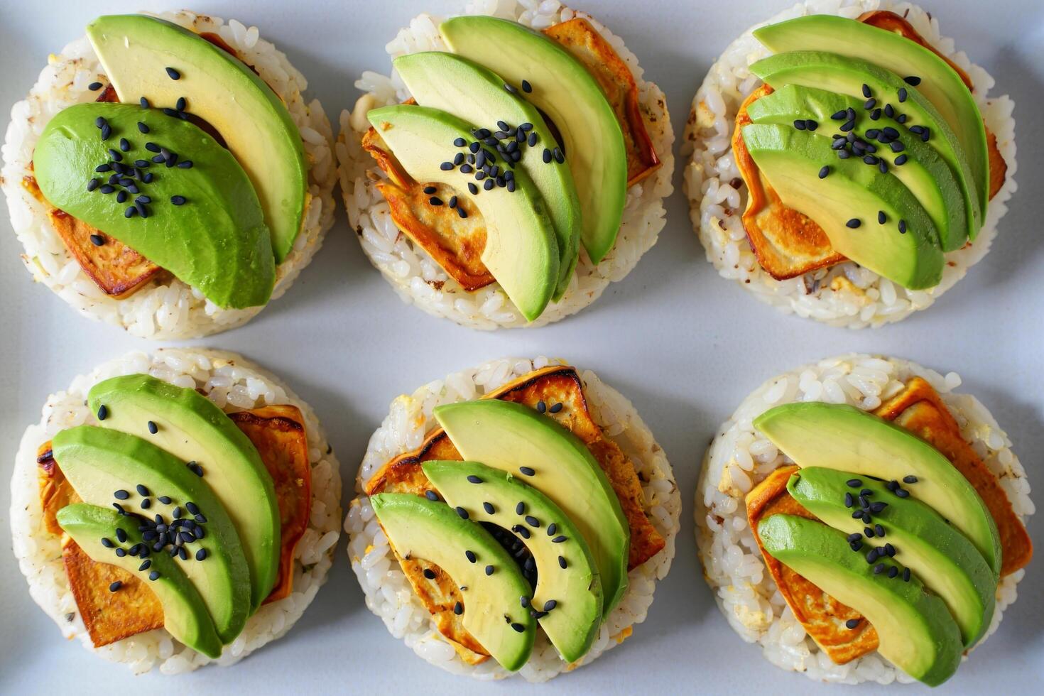 Six healthy avocado and tofu rice cakes topped with black sesame seeds photo