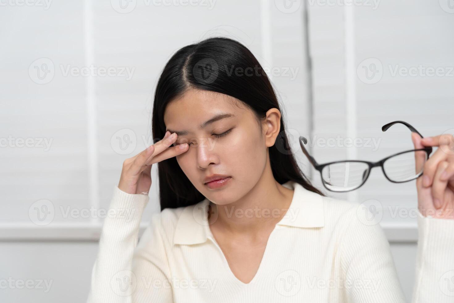 Eye problem. Asian women with tired and irritated eyes, eye rubbing, dry, eye pain after work, migraine, headache, blurred vision, photophobia, working in the dark. photo