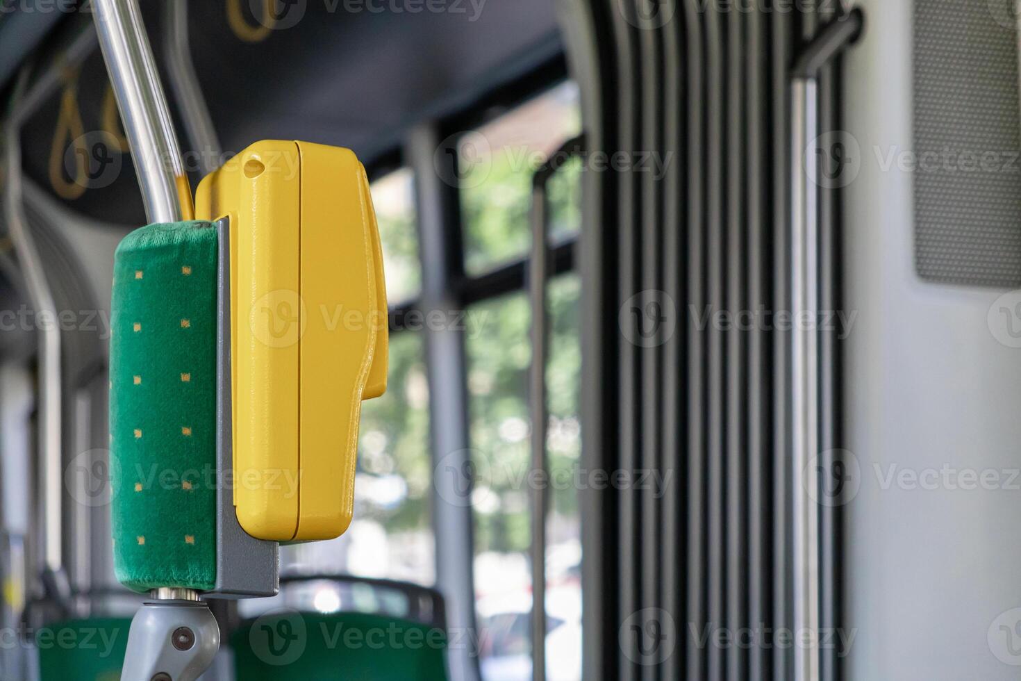 Vivid yellow stop request button and green upholstered safety pole inside a modern public transit bus, representing urban mobility, convenient travel, and passenger accessibility photo