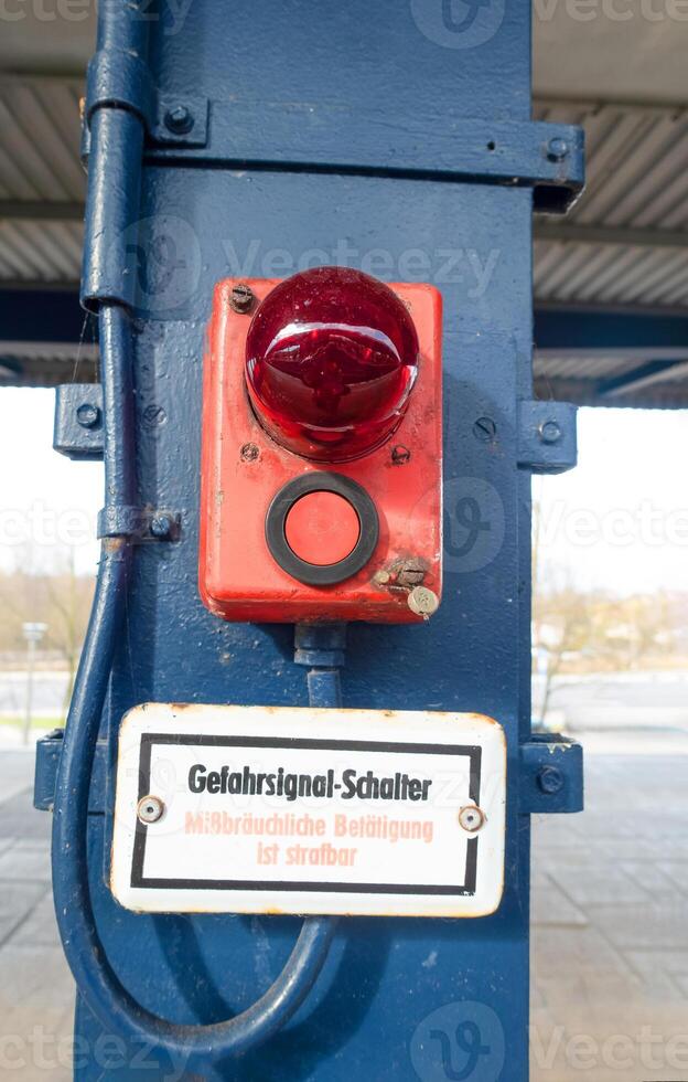 Red emergency signal button mounted on a blue pillar in an industrial setting with clear visibility photo