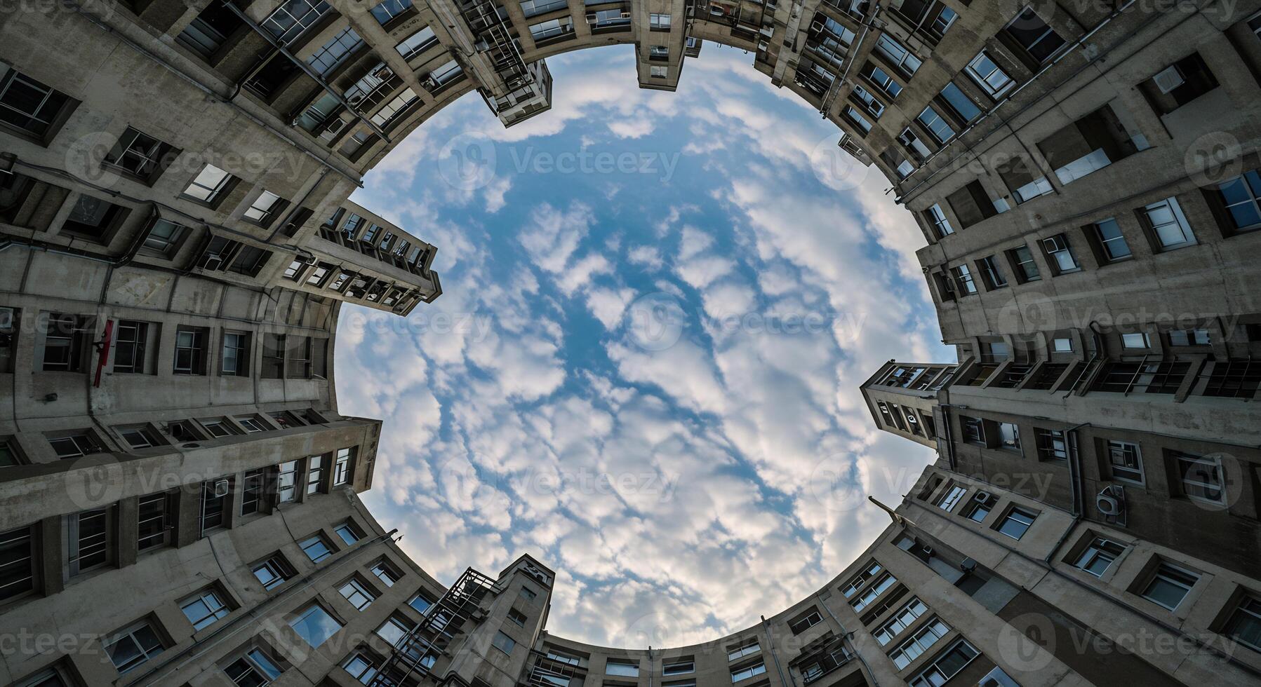 Looking up at a concrete building, a circular view of blue sky with clouds. Urban architecture. photo