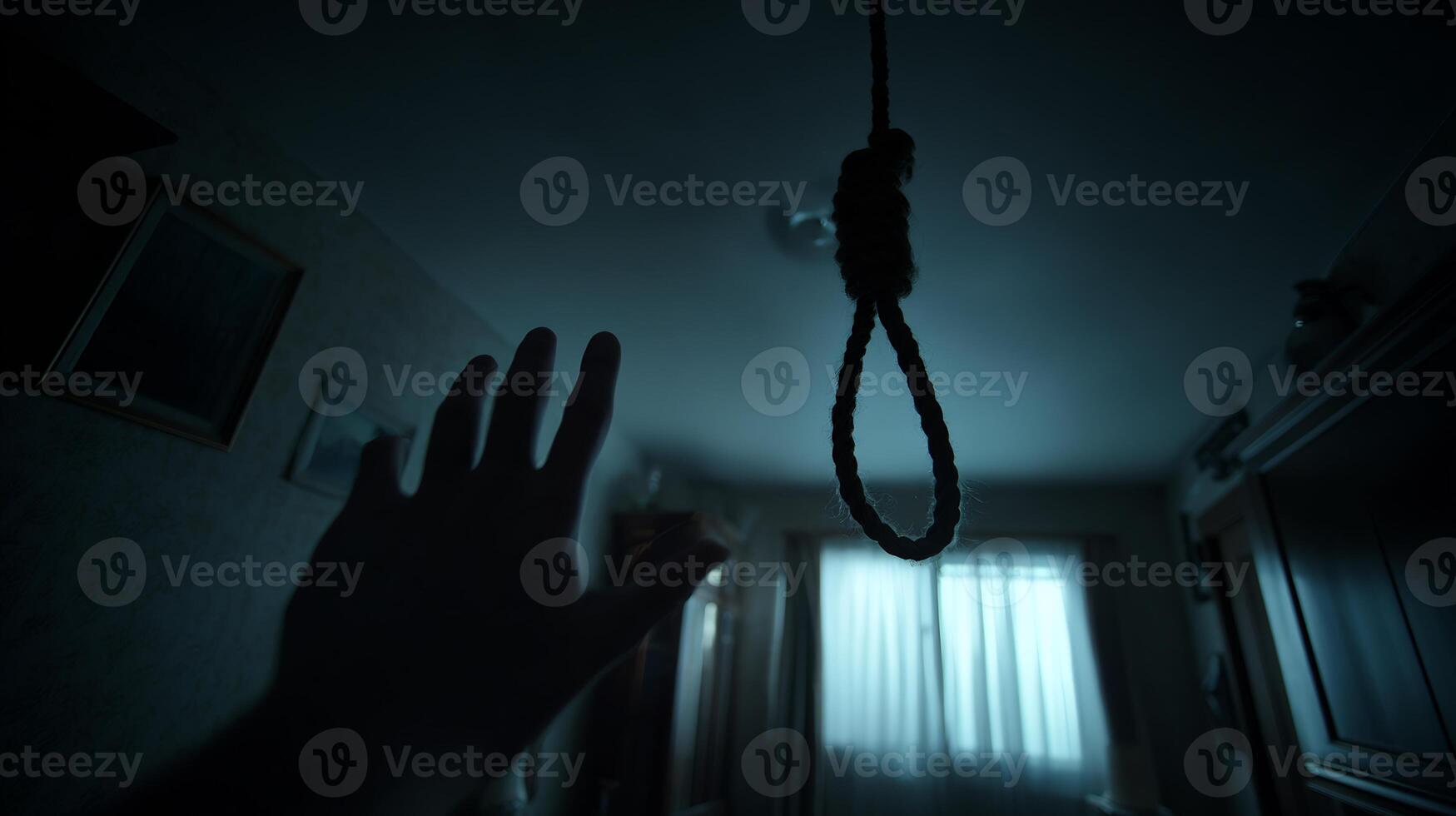 A hand reaches towards a hanging noose in a dimly lit, somber room. photo