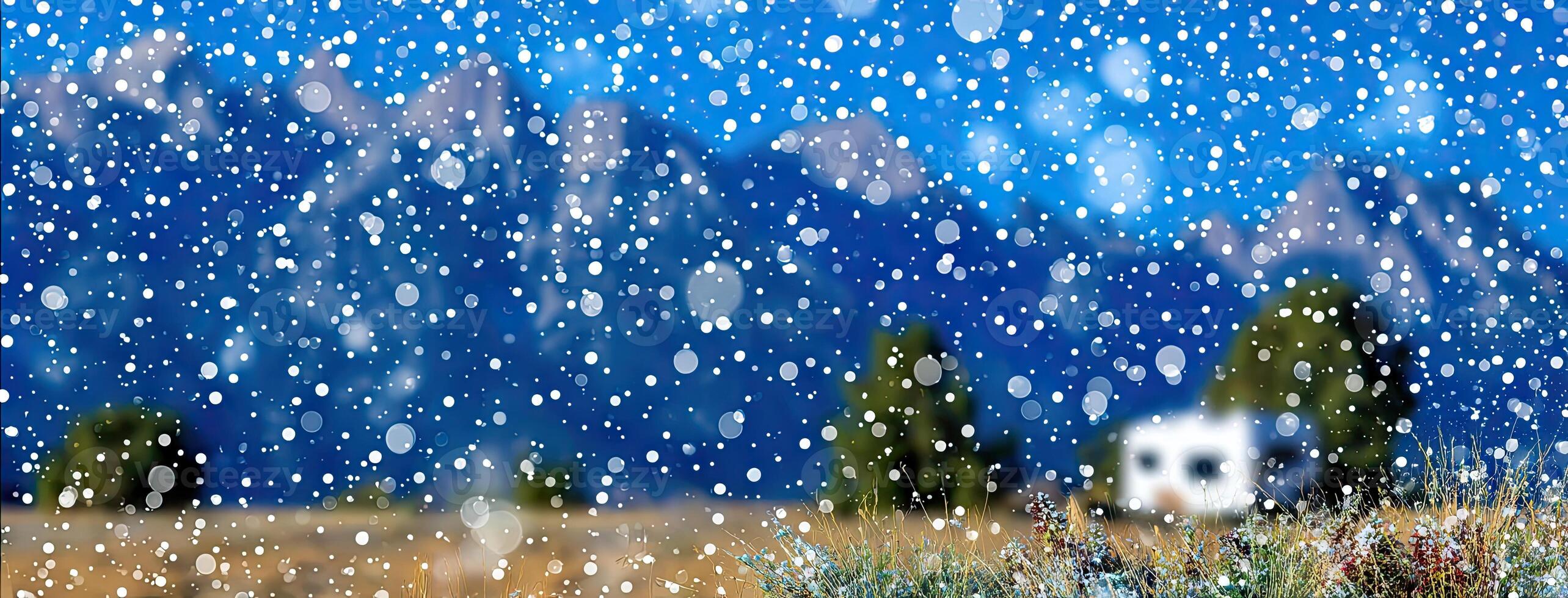 Snow falling on a field with mountains in the background photo