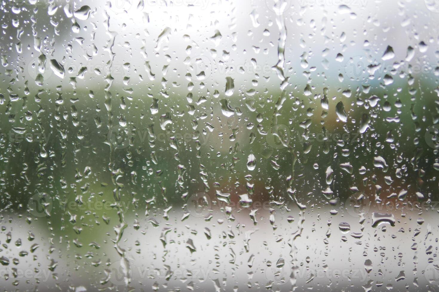 Rain droplets create a serene view on a windowpane photo
